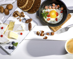 fried eggs in a white black cast-iron frying pan and camembert cheese
