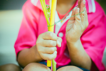 Close-up to kindergarten hands are tied with rubber for to make merit and candle light on Makha Bucha Day