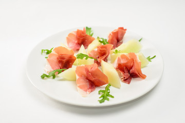 Appetizer from dried meat and cheese with greens