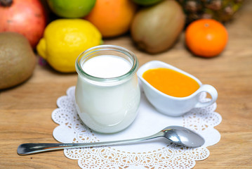 Jar of milk and a saucepan with honey on a background of tropical fruits