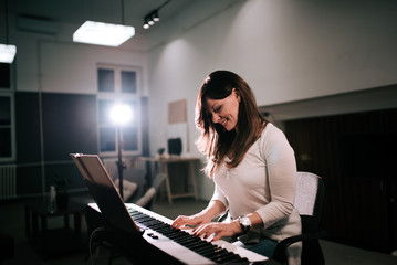 Female composer playing synthesizer piano