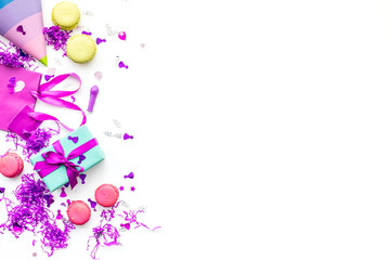 Birthday party accessories. Gift box, paper bag, party hat, sweets, confetti on white background top view copy space