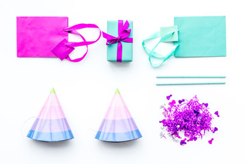 Birthday party accessories. Gift box, paper bag, party hat, confetti on white background top view copy space