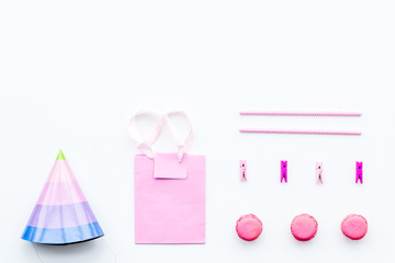 Birthday party accessories. Party hat, sweets, paper bag for gift on white background top view copy space pattern