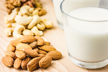 Nut mix, almond, cashew, walnuts and nut milk in glasses on wooden board on concrete background. Selective focus, copy space, closeup. 
