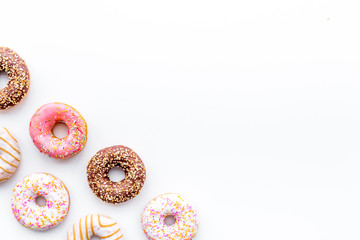 Donuts decorated icing and sprinkles on white background top view copy space pattern