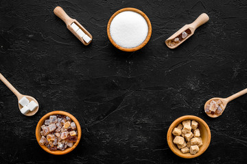Brown and white sugar in bowls, scoop and spoon. Cane, refind, granulated, cubes, candy. Black background top view copy space