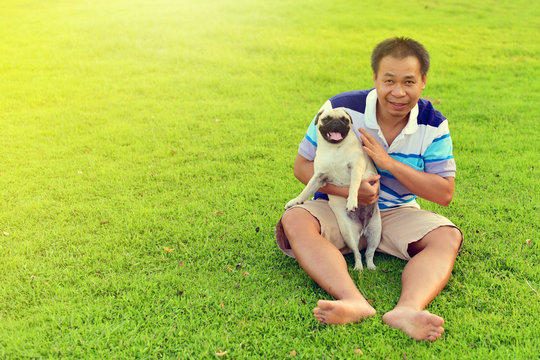 Happy Asian man playing with his dog in garden
