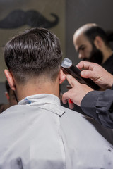 Hairdresser cutting hair to a client with an electric machine