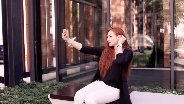 Young, happy woman taking selfie photo with cellphone in the city
