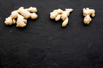 Whole ginger roots on black background top view space for text