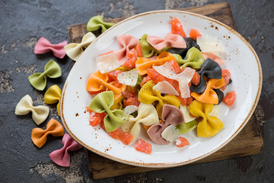 Plate of boiled farfalle served with salmon and cheese, brown stone background, horizontal shot
