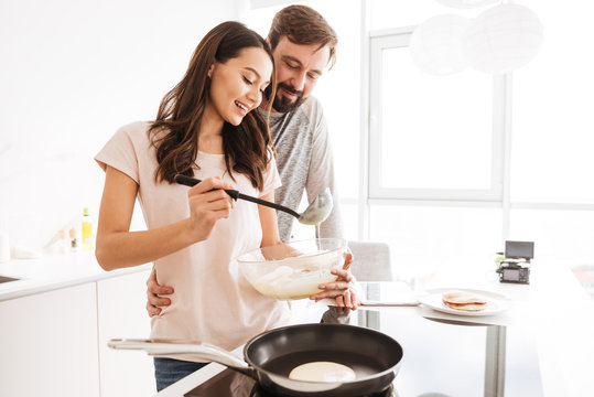 Portrait of a happy young couple cooking pancakes