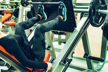 Young sporty woman does leg exercises in gym