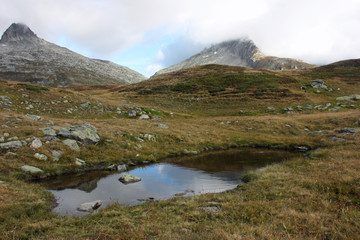 Fototapeta na wymiar Swiaa Alps Scenery with low clouds and pond