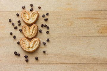 Cookies in the form of heart on a light wooden background and decorated with coffee beans. Copy text menu food background.Top View, Flat. Horizontal Background.