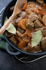 Closeup of Irish traditional beer and beef stew in a cast-iron pan, vertical shot, elevated view