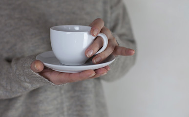 Female hands holding white cup with hot tea or coffee. Tea break. Winter, warm and cozy time concept.