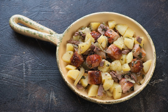Portion of Dublin coddle or traditional Irish potato, sausage and bacon stew, dark brown stone background, horizontal shot