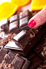 tablet and pieces of dark chocolate with woman finger