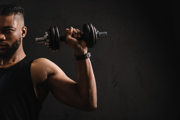 Fototapeta na wymiar cropped shot of muscular african american man training with dumbbell isolated on black
