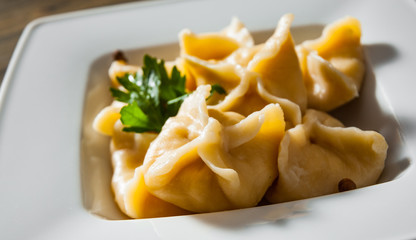 Meat dumplings - russian pelmeni, ravioli with meat on plate on a wooden background