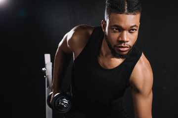 Fototapeta na wymiar handsome young african american sportsman exercising with dumbbell in gym