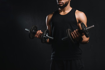 Fototapeta na wymiar cropped shot of muscular african american man exercising with dumbbells isolated on black