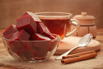 Natural cherry jam served with tea, cinnamon sticks in rustic style on burlap