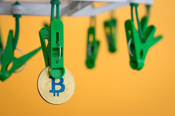 Fototapeta premium Green clothes peg hold one gold Bitcoin