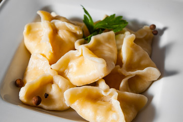 Meat dumplings - russian pelmeni, ravioli with meat on plate on a wooden background