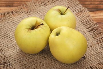 Three green ripe apples on burlap background