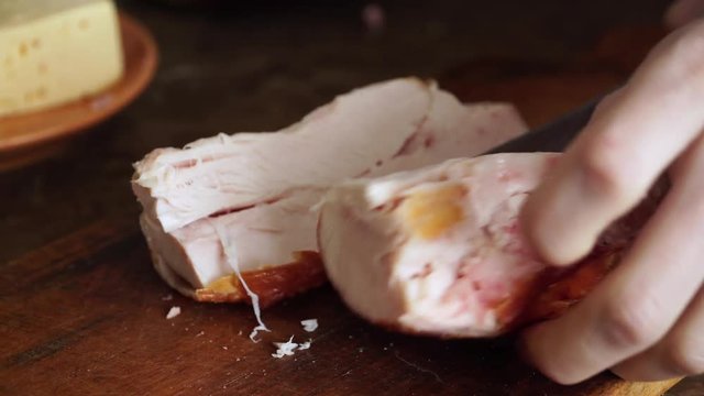 Woman cuts smoked chicken breast with sharp knife