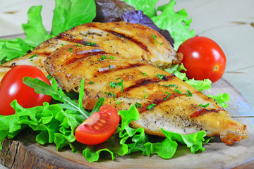 Grilled chicken breast with nutritious green leaf vegetables, arugula, lettuce, spinach, cherry tomatoes and avocado.