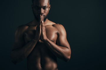 serious shirtless young african american sportsman looking at camera isolated on black