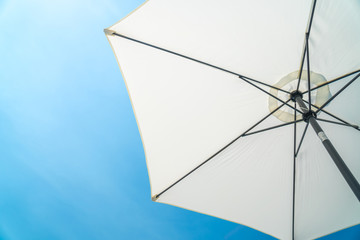 The white opened beach umbrella on a background of the blue sky