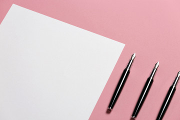 Three Pens Lies On A Blank Sheet Of Paper On Pink Background, Top View. Office Space Creativity Minimalism Concept