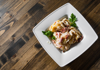 Meat dumplings - russian pelmeni, ravioli with meat on plate on a wooden background