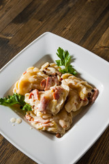 Meat dumplings - russian pelmeni, ravioli with meat on plate on a wooden background