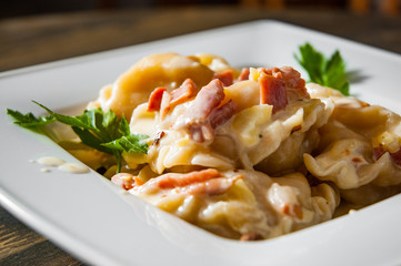 Meat dumplings - russian pelmeni, ravioli with meat on plate on a wooden background