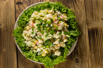 Obraz na płótnie Canvas Salad with crab sticks, sweet corn, cucumber, eggs, rice and mayonnaise