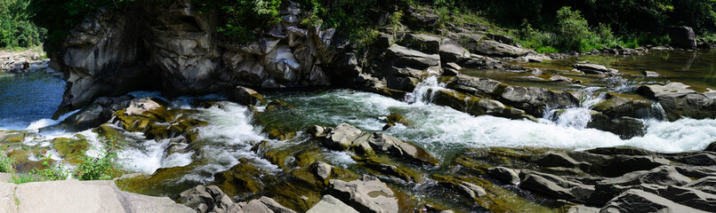 Panorama of a mountain river among rocks and stones waterfall