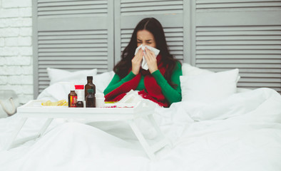 Very high body temperature. A young sick woman in a red scarf measures the temperature with a thermometer. The concept of health and disease.