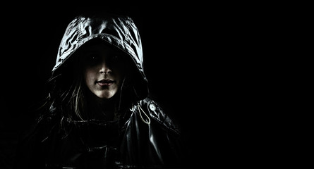 Mysterious girl in a hood on a black background.