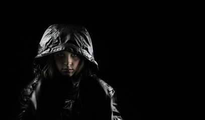 Fototapeta na wymiar Mysterious girl in a hood on a black background.