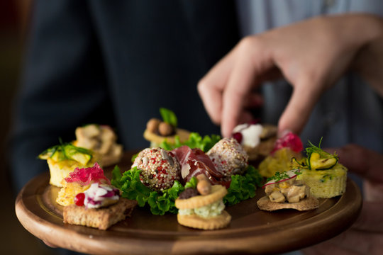 Woman's hand picking food appetizer from a plate