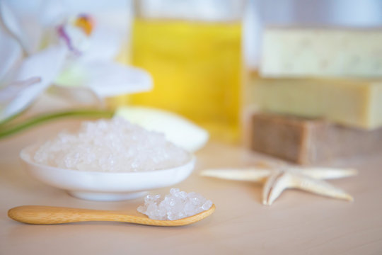 Wellness setting. Sea salt, soap, towel, oil and flowers on wooden background, spa