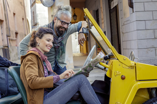 Woman and man smiling looking at map.Side view. Caucasian couple in love roadtrip vacation italian travel on convertible car