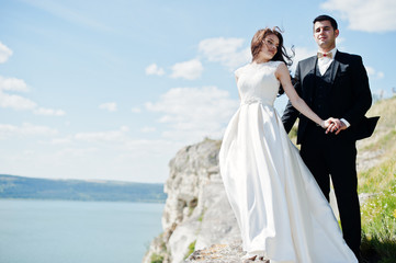Fototapeta na wymiar Wedding couple at breathtaking landscape with rock and lake.
