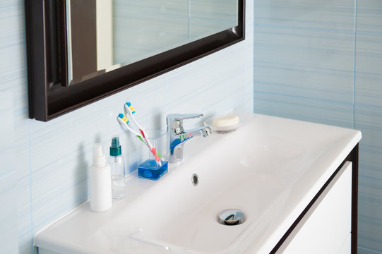 bright blue white bathroom with wash basin with toothbrush and chrome mixer